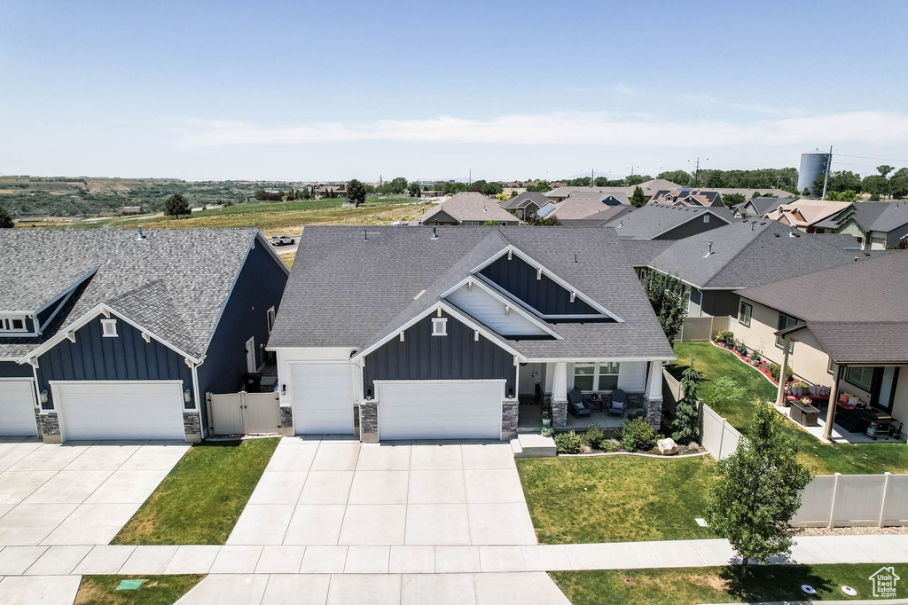 View of front of house featuring board and batten siding, a garage, stone siding, driveway, and a shingled roof