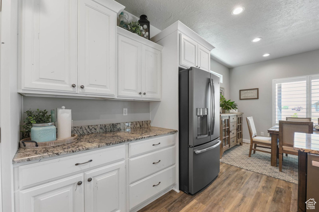 Kitchen with stainless steel fridge, white cabinetry, dark wood finished floors, recessed lighting, and a textured ceiling