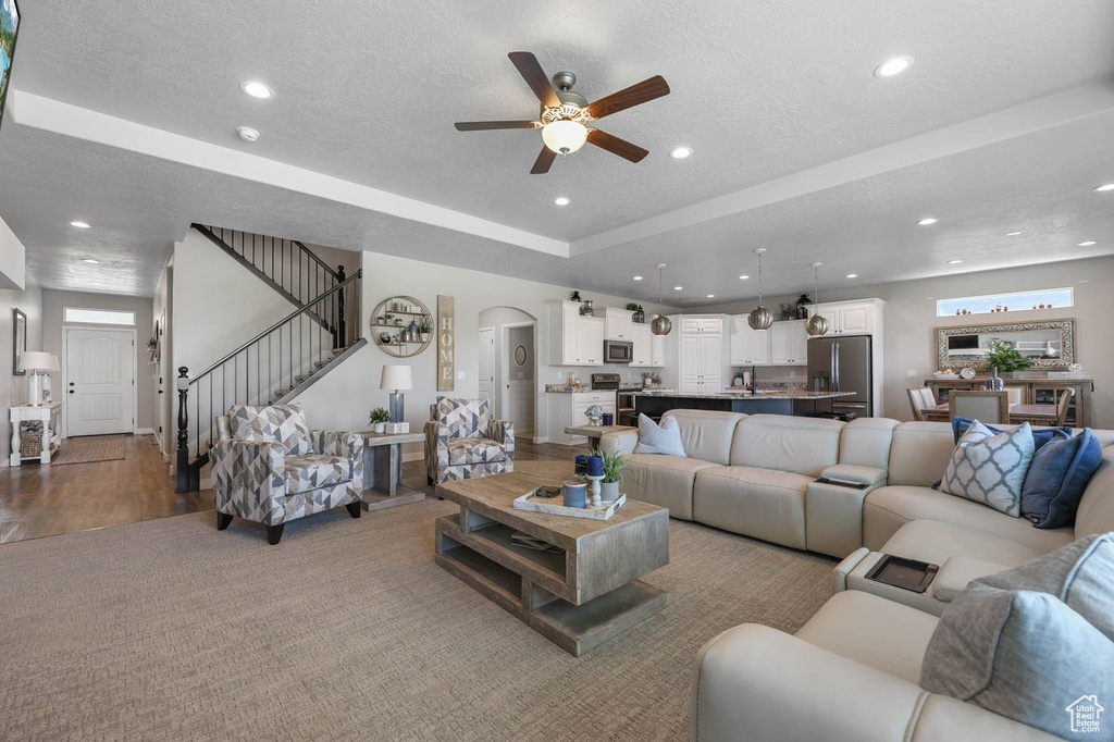 Living room featuring ceiling fan, recessed lighting, stairs, a textured ceiling, and arched walkways