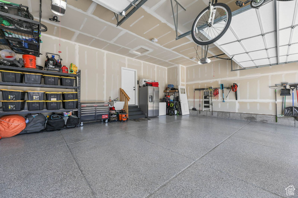 Garage featuring stainless steel fridge with ice dispenser and a garage door opener