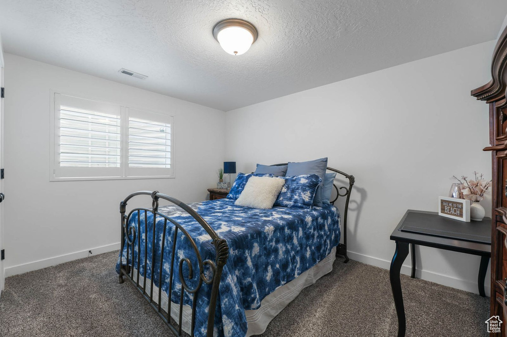 Carpeted bedroom with a textured ceiling and baseboards