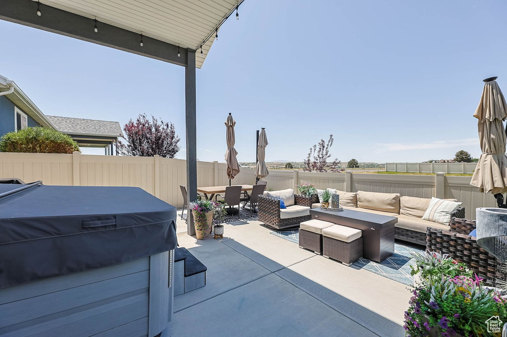 Fenced backyard featuring a hot tub, an outdoor hangout area, a patio area, and outdoor dining space