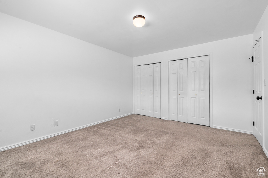 Unfurnished bedroom with carpet flooring and multiple closets