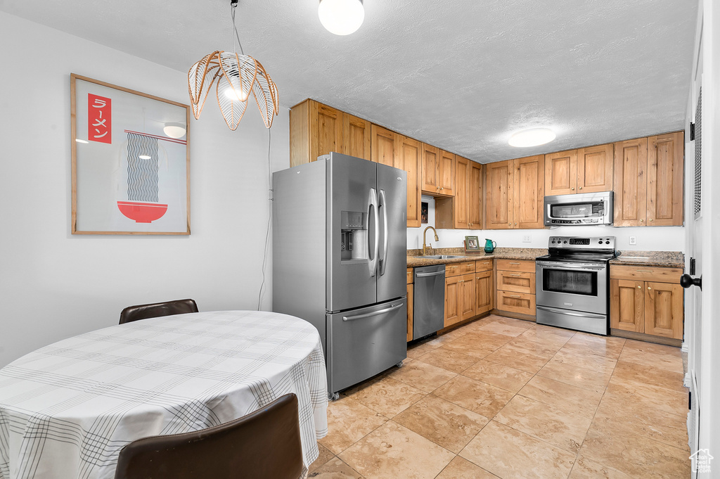 Kitchen featuring stainless steel appliances, stone counters, and a textured ceiling