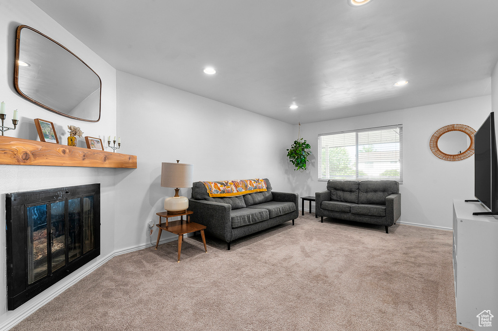 Living area featuring carpet flooring, recessed lighting, and a glass covered fireplace