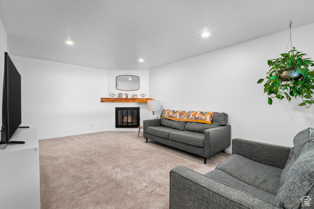 Living room with a glass covered fireplace, recessed lighting, and carpet floors