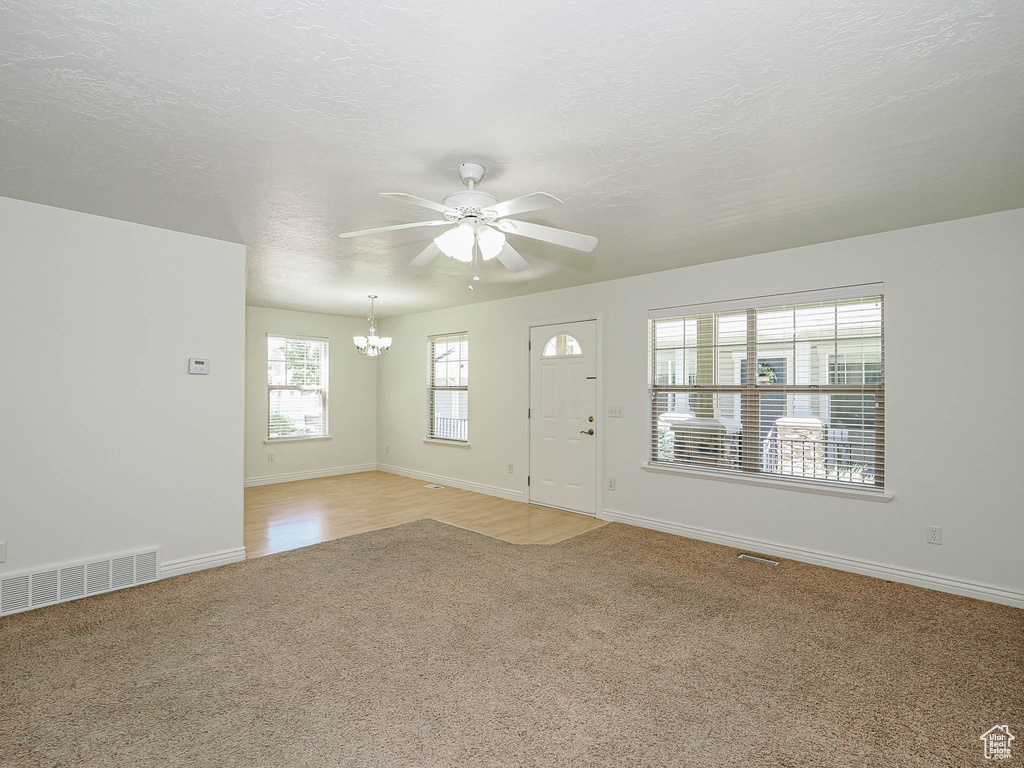 Entrance foyer with light carpet, ceiling fan, and a chandelier