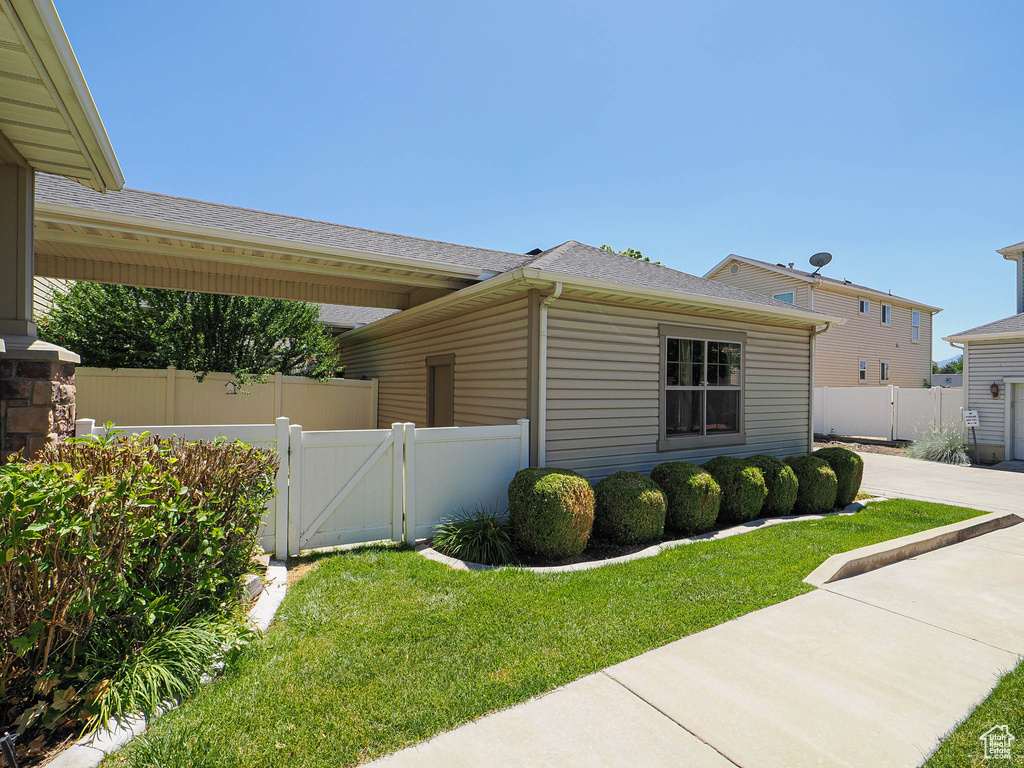 View of side of home featuring a gate, roof with shingles, and a patio