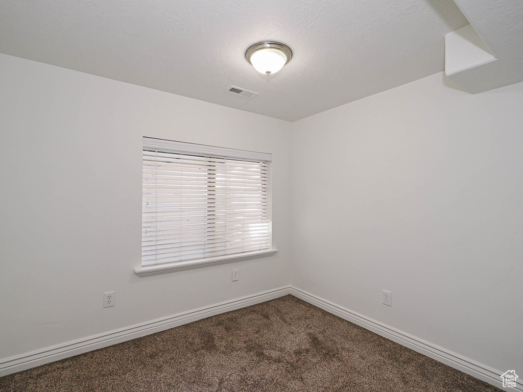 Carpeted spare room featuring baseboards and a textured ceiling