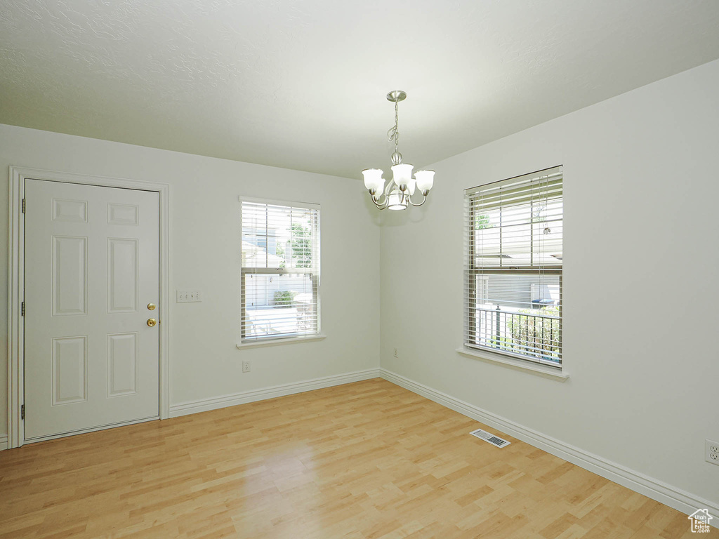 Spare room featuring a chandelier, plenty of natural light, and light wood-style flooring
