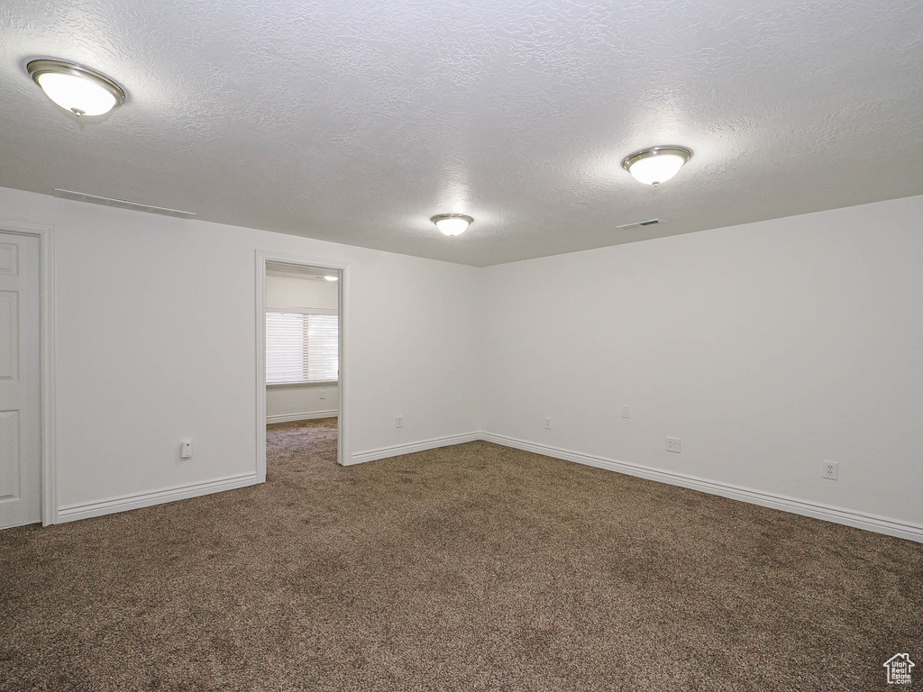 Unfurnished room featuring carpet and a textured ceiling