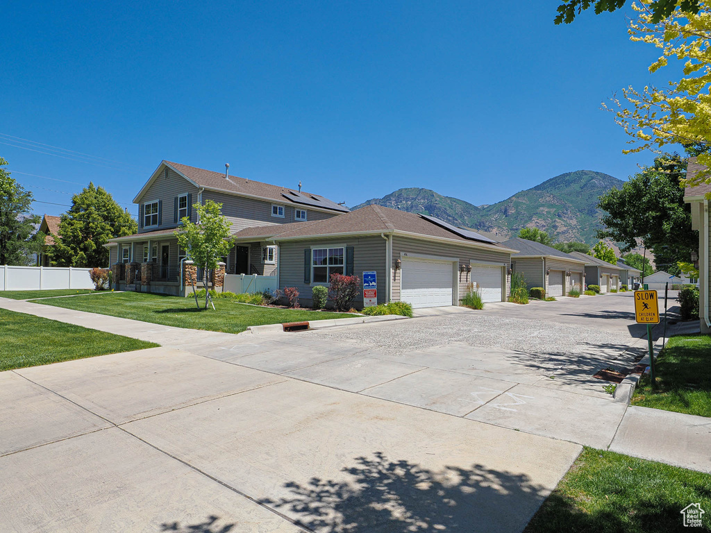View of front of house with solar panels, a mountain view, concrete driveway, and an attached garage