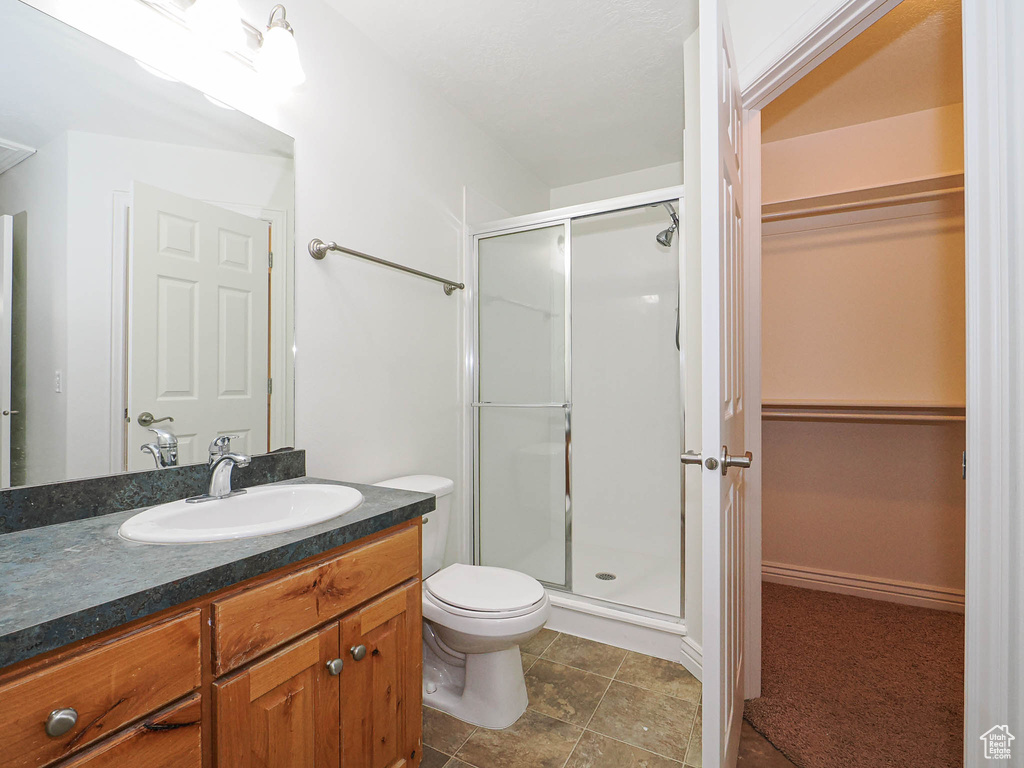 Bathroom featuring a shower stall, a spacious closet, and vanity