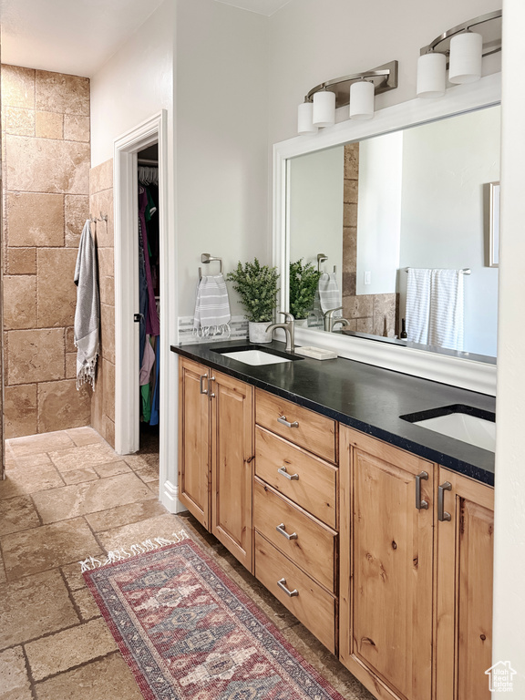 Bathroom with double vanity, stone tile flooring, and a spacious closet