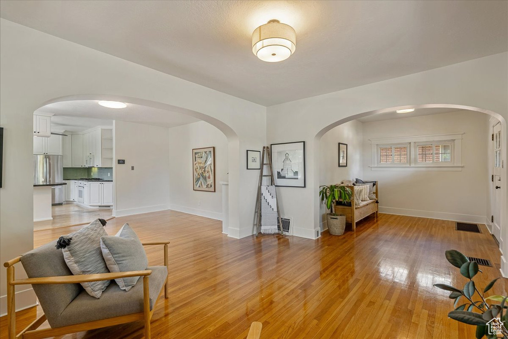Living area with arched walkways and light wood finished floors