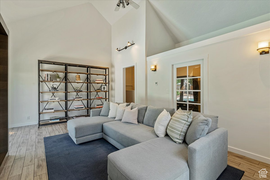Living area featuring light wood-style flooring, high vaulted ceiling, and a ceiling fan