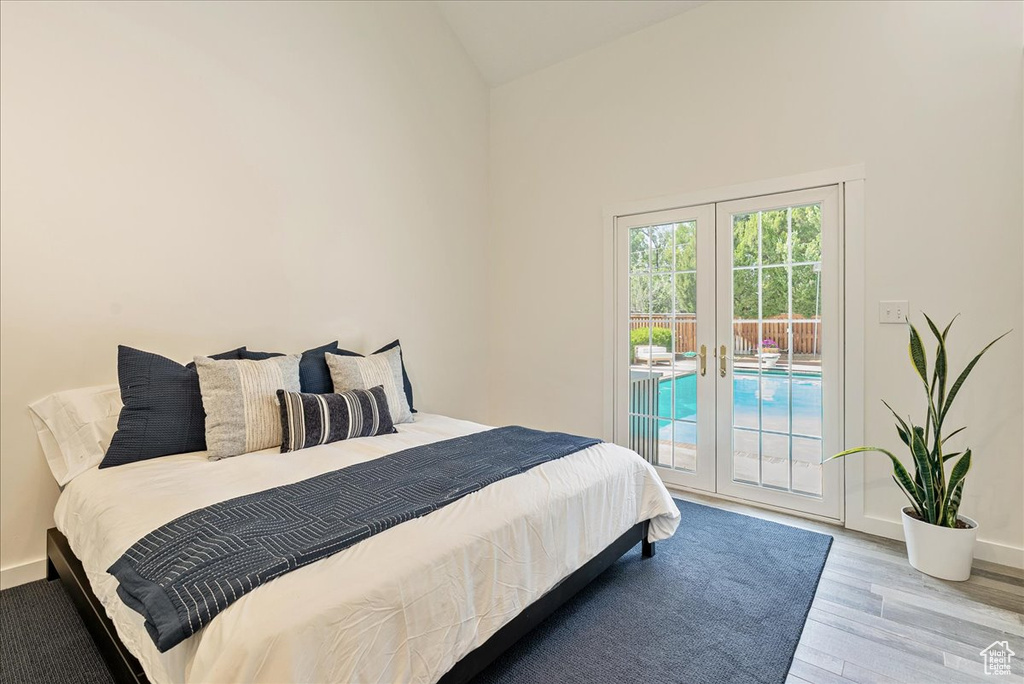 Bedroom featuring french doors, access to exterior, wood finished floors, and high vaulted ceiling
