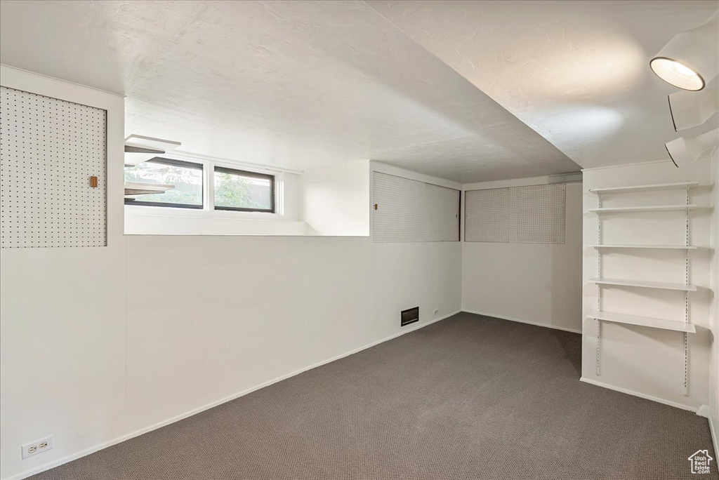 Basement with dark carpet and baseboards
