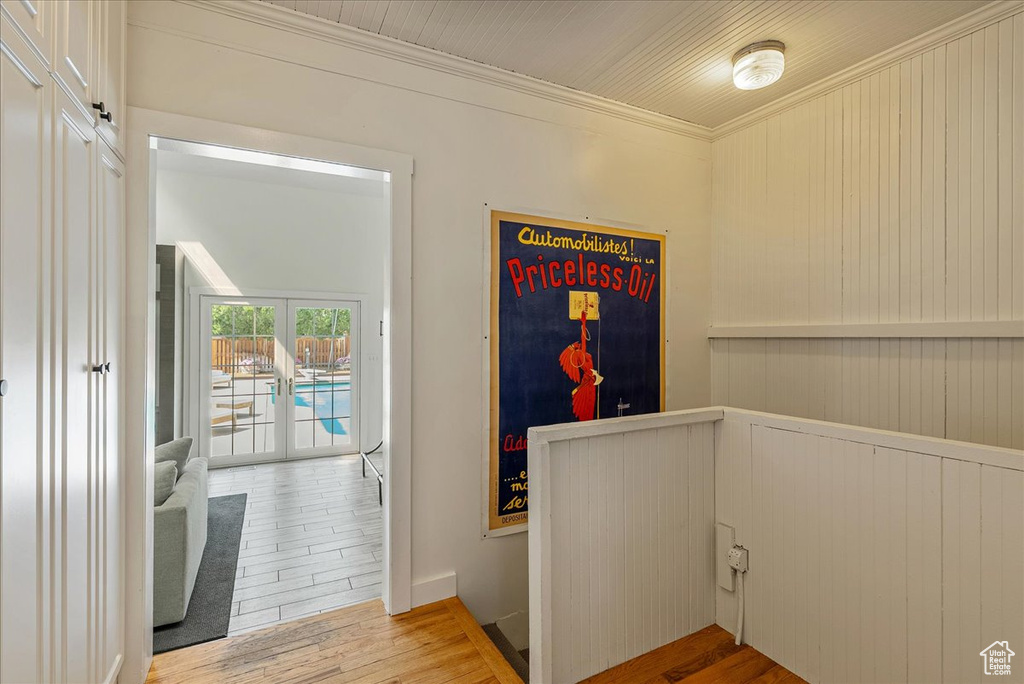 Corridor with wood finished floors, crown molding, and an upstairs landing