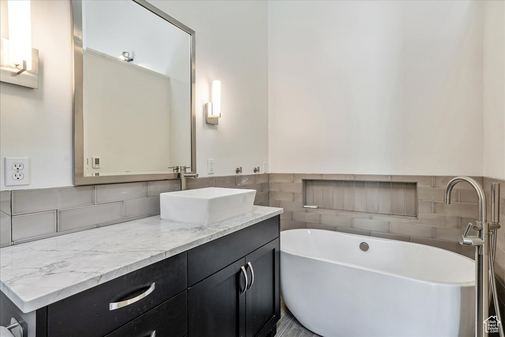 Bathroom featuring a freestanding tub, vanity, and tile walls