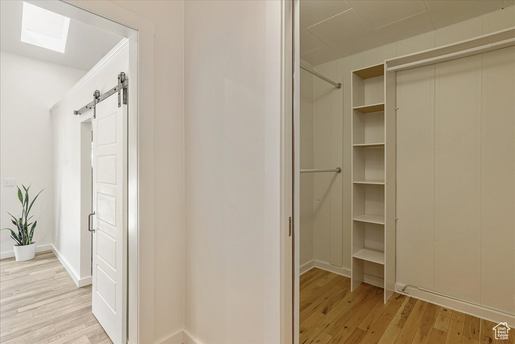 Walk in closet with light wood-style flooring, a barn door, and a skylight