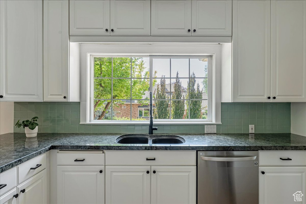Kitchen featuring dishwasher, white cabinets, plenty of natural light, and tasteful backsplash