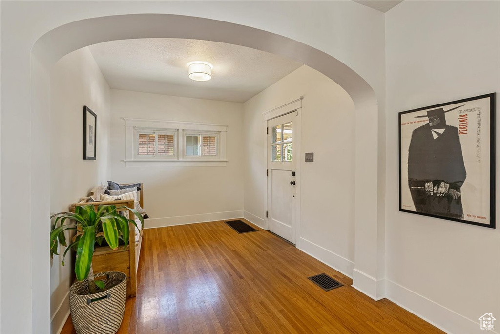 Foyer with arched walkways and wood finished floors
