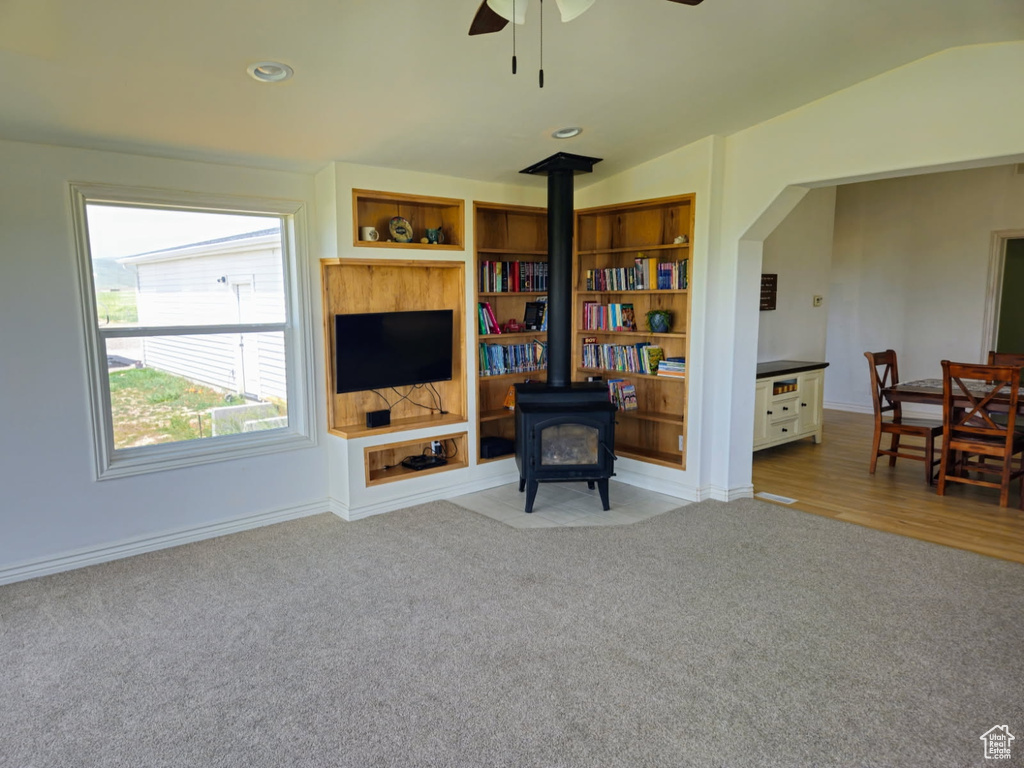 Living area with a wood stove, carpet flooring, ceiling fan, vaulted ceiling, and recessed lighting