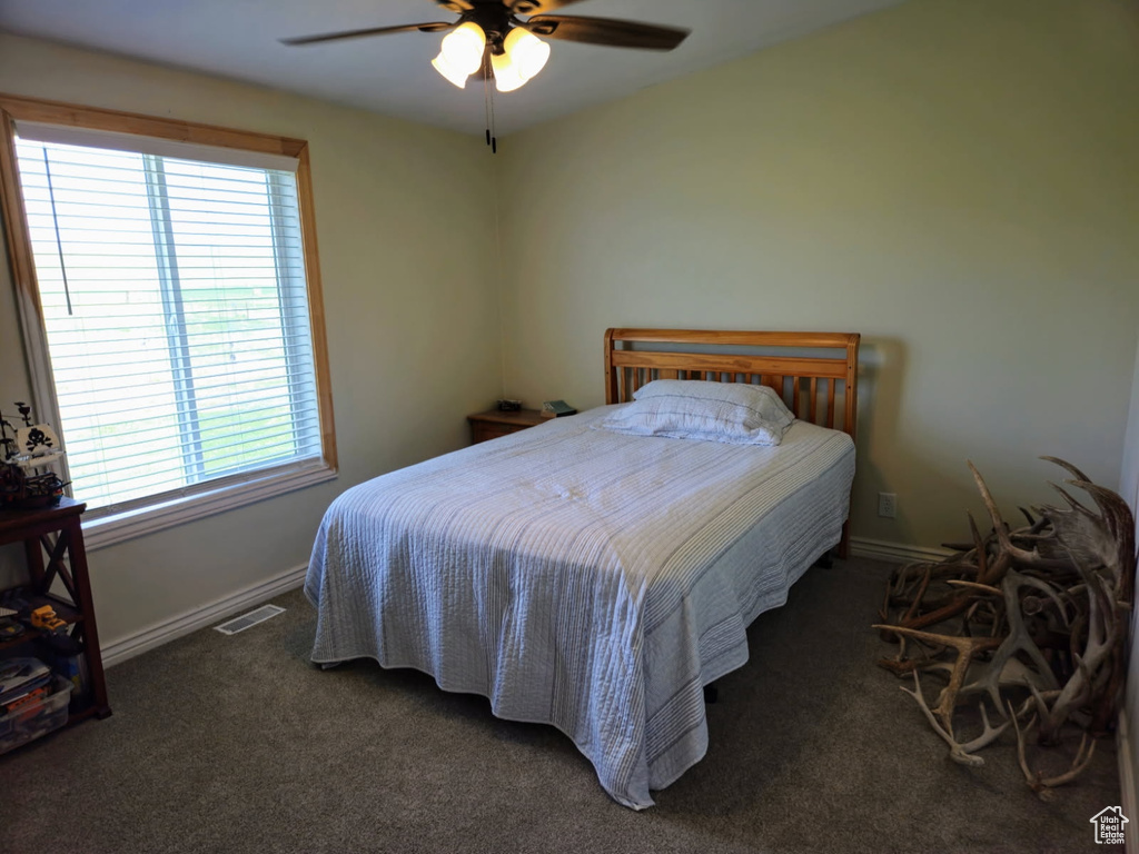 Carpeted bedroom with a ceiling fan and baseboards