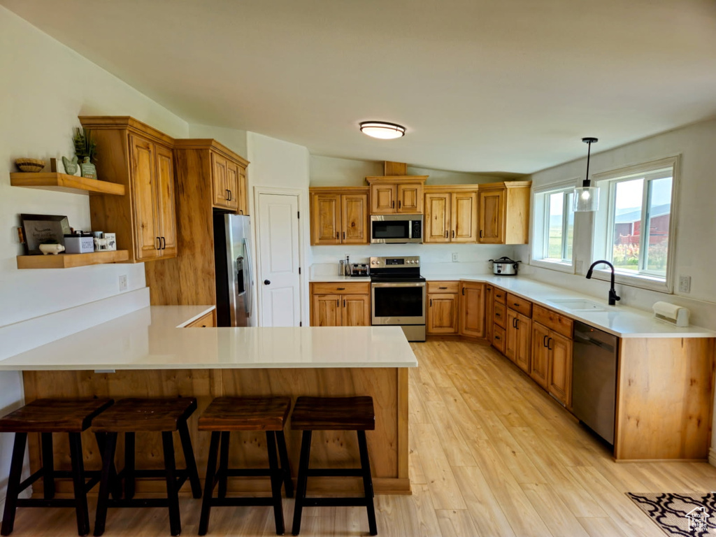 Kitchen with stainless steel appliances, open shelves, a peninsula, vaulted ceiling, and light countertops