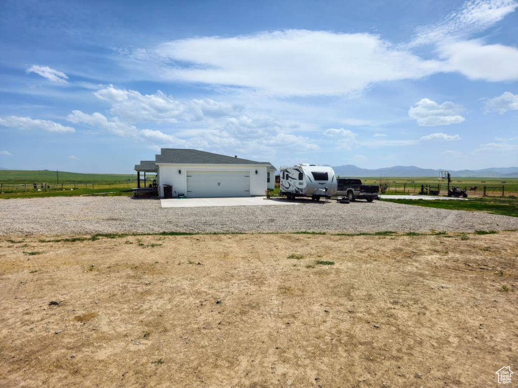View of yard featuring a view of rural / pastoral area, driveway, a mountain view, and an attached garage