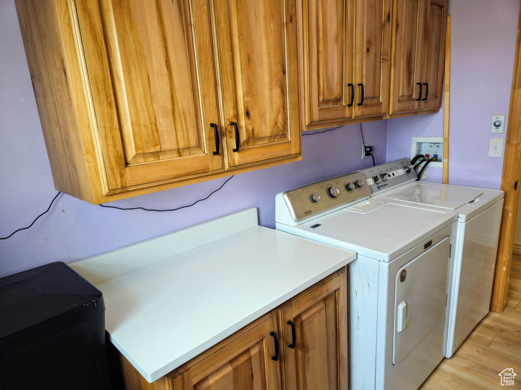Washroom featuring cabinet space, washer and dryer, and light wood finished floors