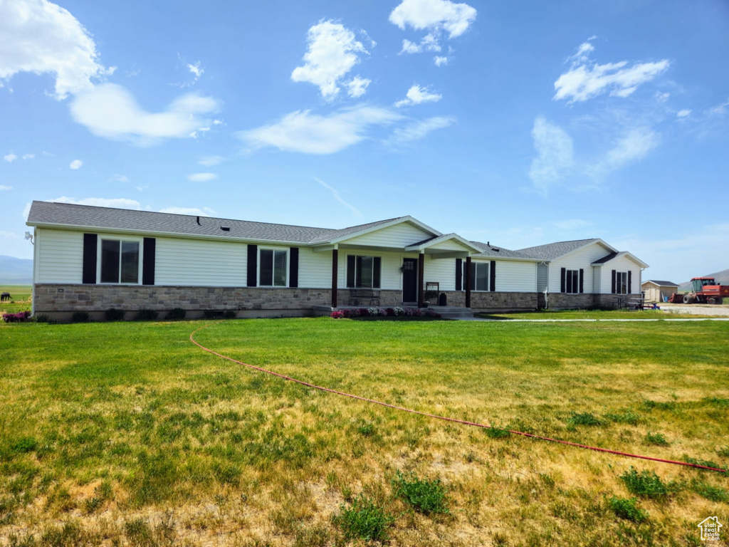 Ranch-style home featuring a front lawn and stone siding