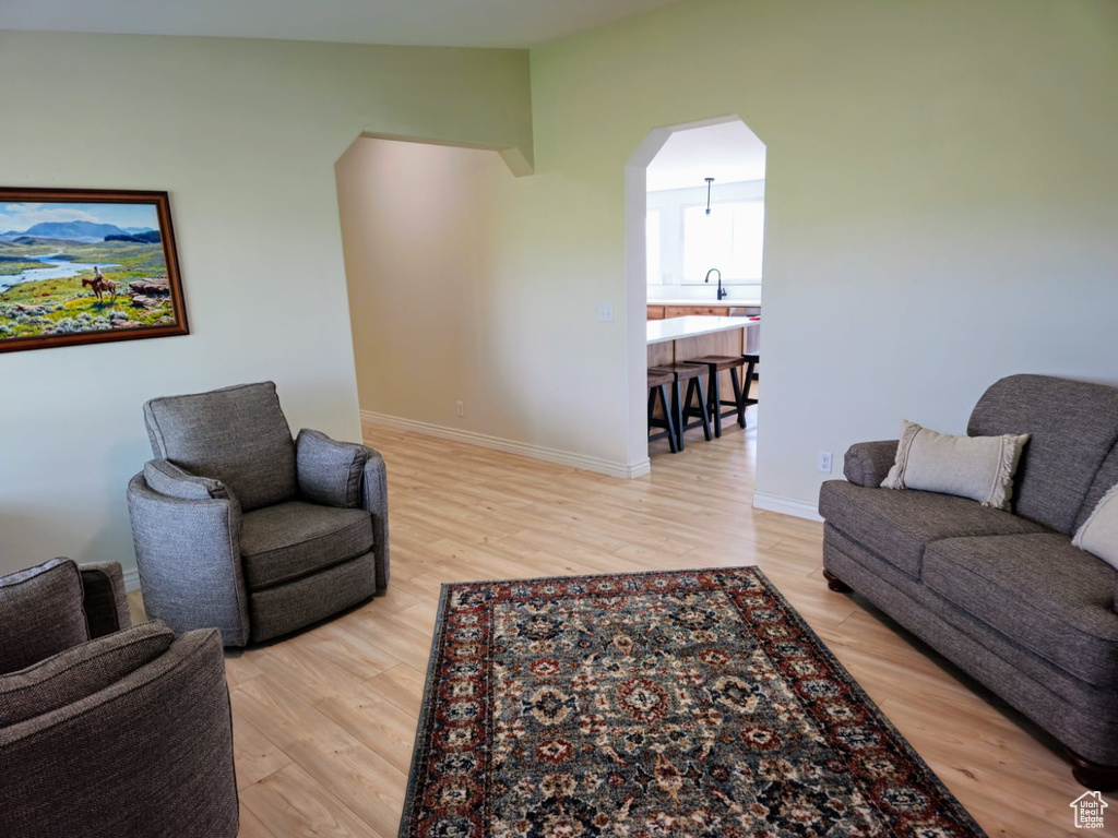 Living room with arched walkways, light wood finished floors, and lofted ceiling