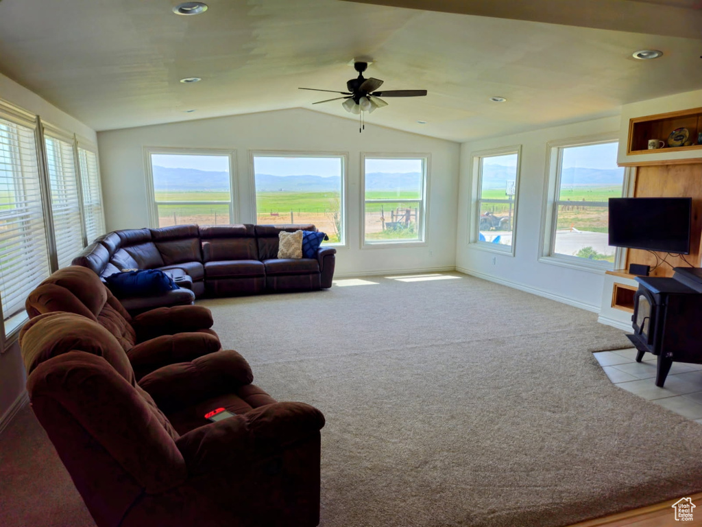 Carpeted living area featuring ceiling fan, a wood stove, lofted ceiling, and recessed lighting