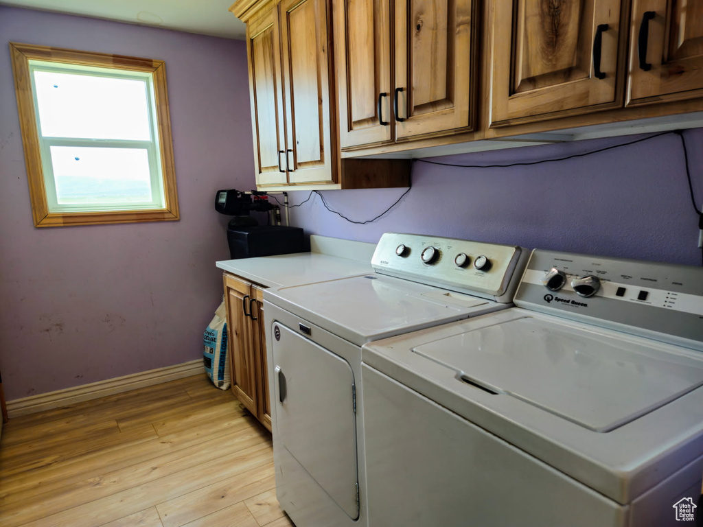 Laundry room featuring washing machine and dryer, light wood finished floors, and cabinet space