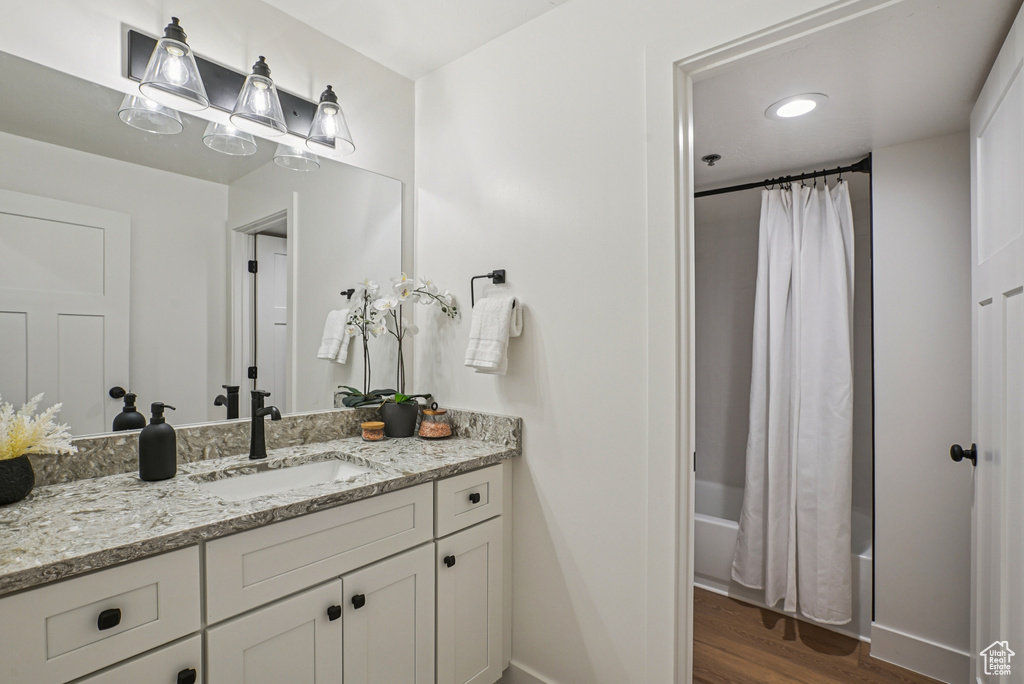 Full bath featuring vanity, wood finished floors, and shower / tub combo with curtain