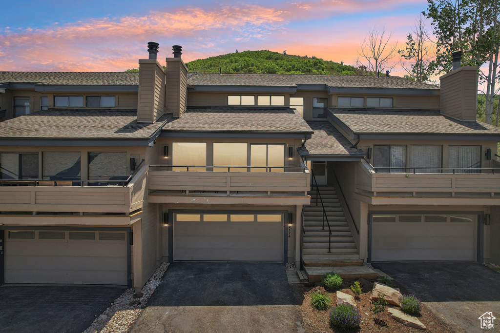 View of front of property with a chimney, an attached garage, driveway, and stairs