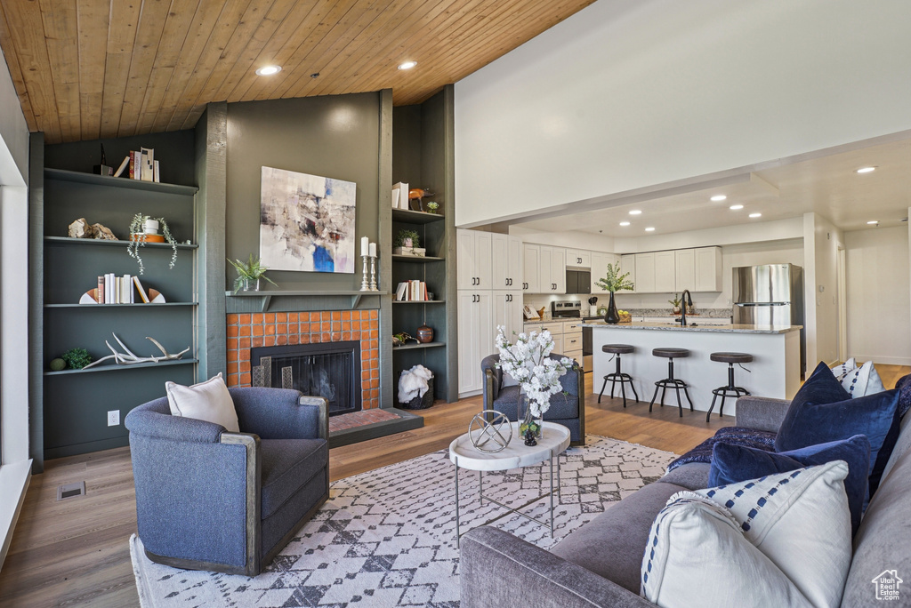 Living room featuring wood finished floors, recessed lighting, wooden ceiling, a fireplace, and built in features