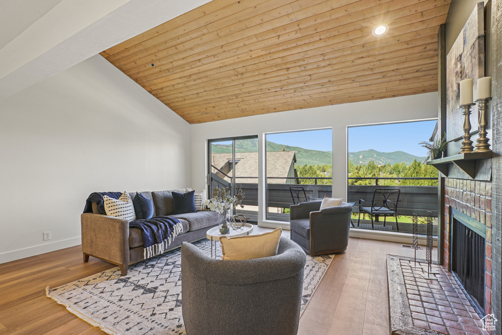 Living room with high vaulted ceiling, a fireplace, wood ceiling, wood finished floors, and a mountain view