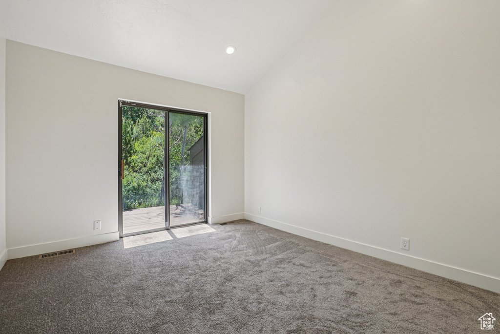 Carpeted empty room featuring lofted ceiling and baseboards