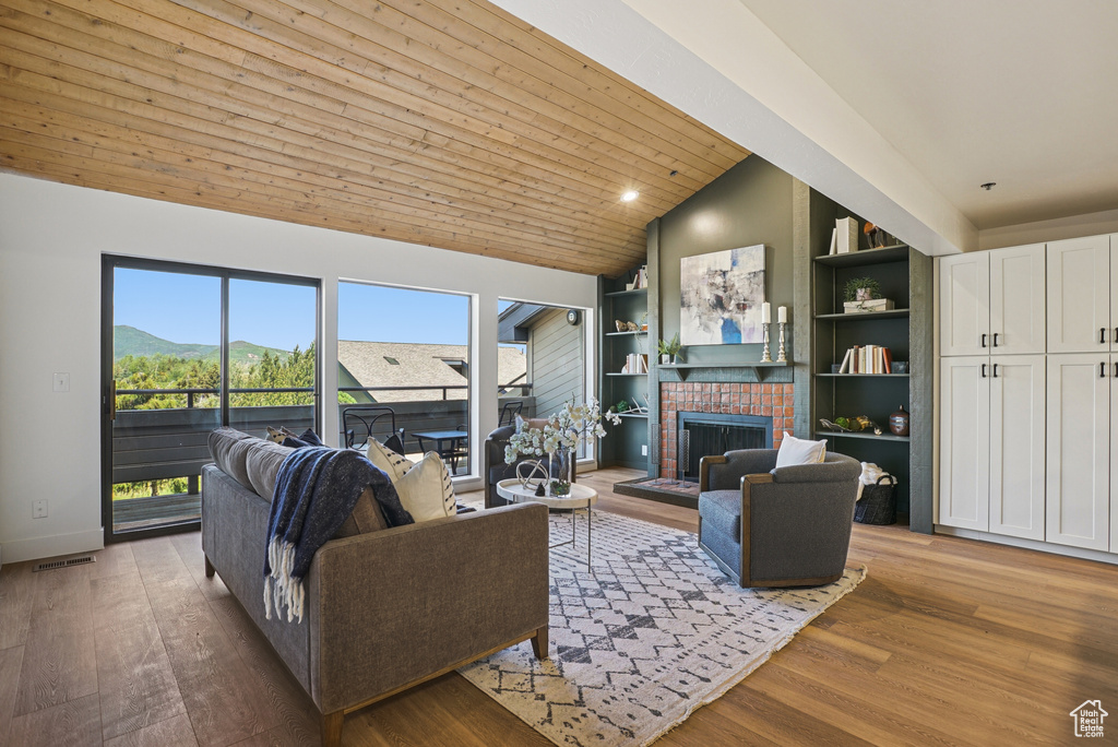 Living room featuring a fireplace, wood finished floors, high vaulted ceiling, and built in shelves