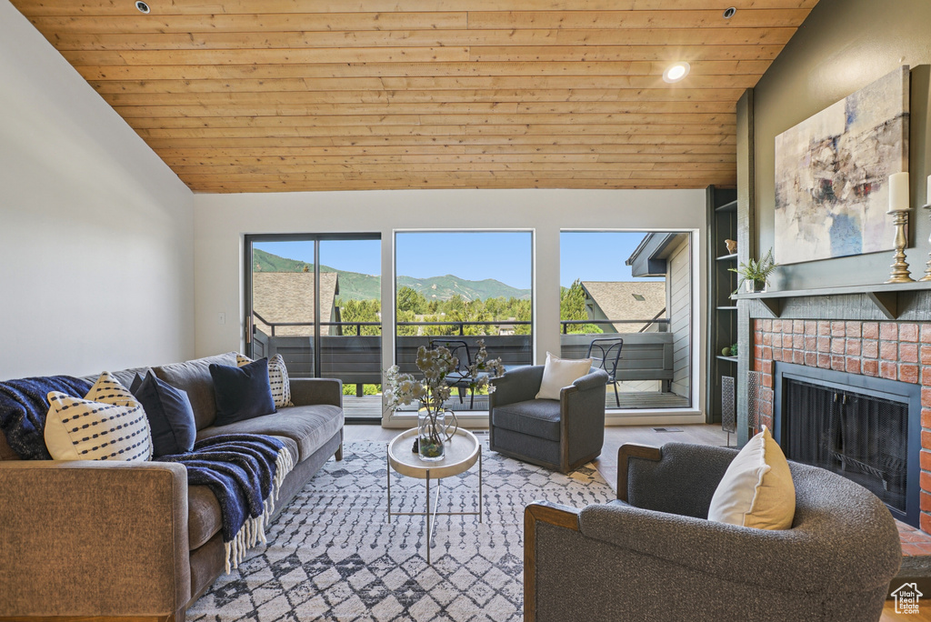 Living room with wood ceiling, vaulted ceiling, a fireplace, a mountain view, and recessed lighting
