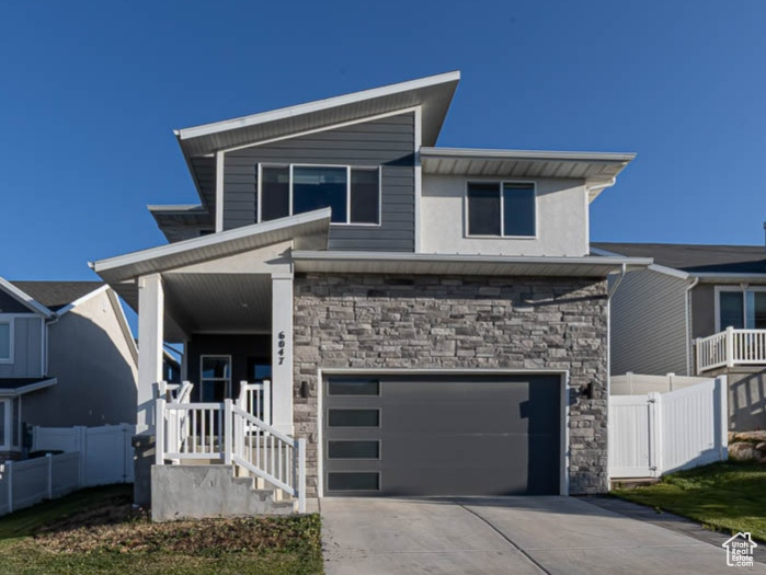 Contemporary house featuring a garage, stairway, stone siding, and concrete driveway