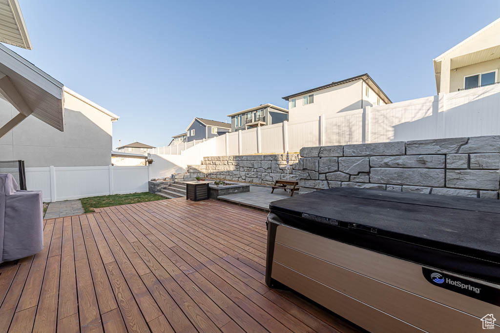 Deck with a hot tub, a fenced backyard, and a residential view