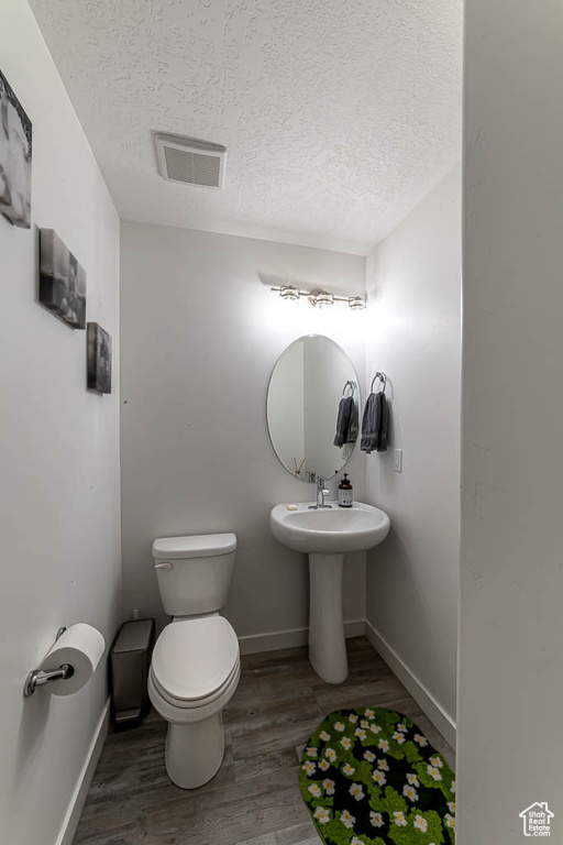 Bathroom with a textured ceiling and wood finished floors