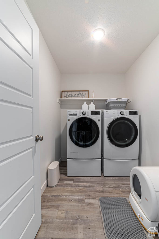 Washroom featuring washer and dryer, wood finished floors, and a textured ceiling