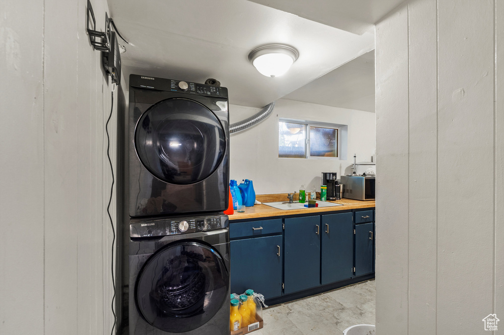 Laundry area featuring stacked washer / dryer and a sink