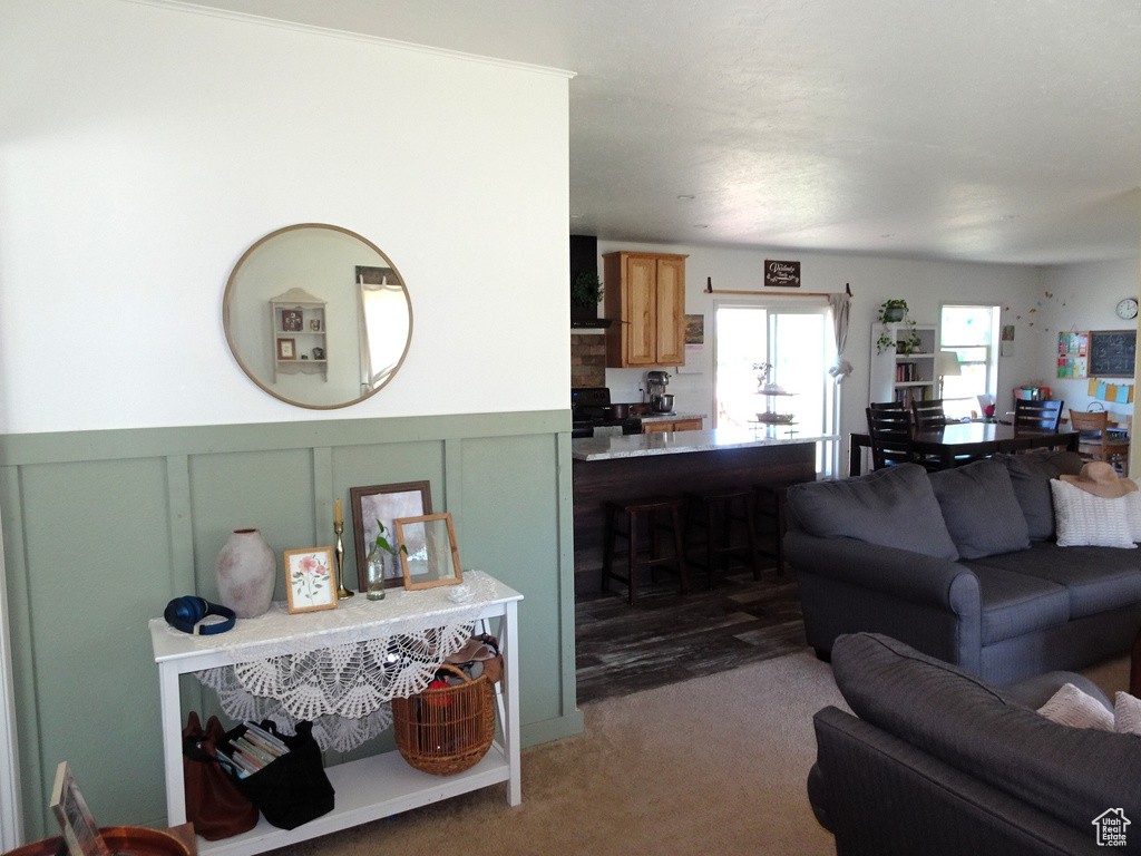 Living room with carpet floors, wainscoting, and a decorative wall