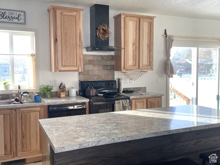 Kitchen featuring wall chimney range hood, black appliances, light countertops, a kitchen breakfast bar, and a textured ceiling